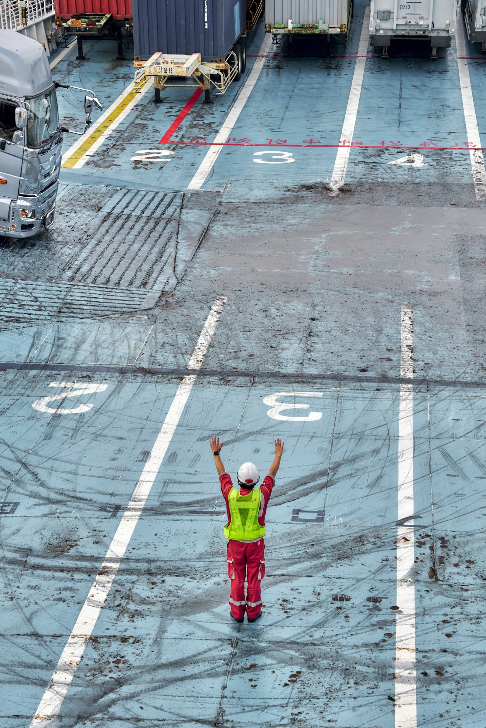Port worker in hi-vis signaling on a vessel loading deck