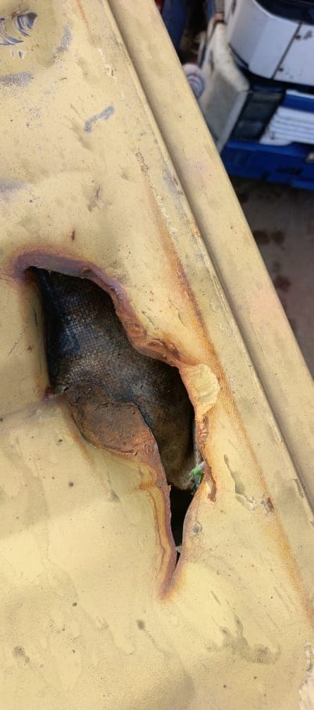 Rusted hole damage in a shipping container wall